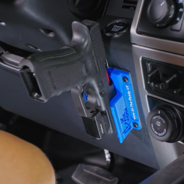 Blue At The Ready pistol mount installed on a vehicle side panel beside the dashboard controls